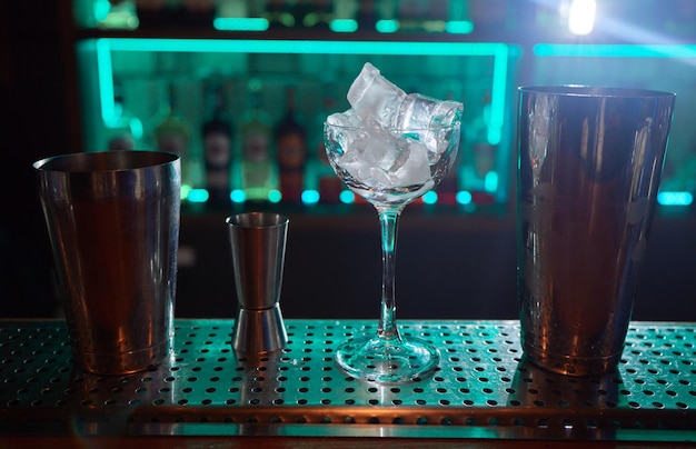 Barman w koszuli i fartuchu robi napój alkoholowy z lodem w kieliszku koktajlowym