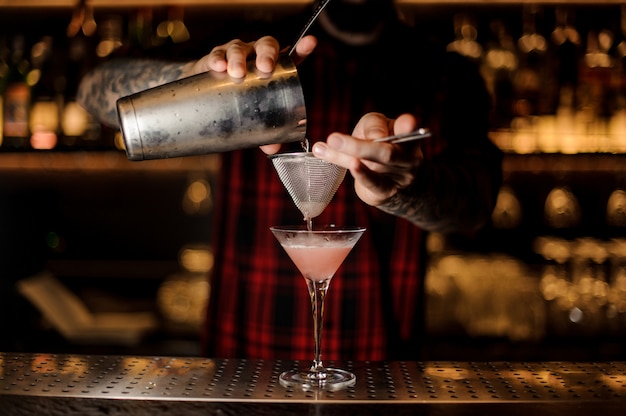 Barman wlewa Cosmopolitan koktajl do szklanki