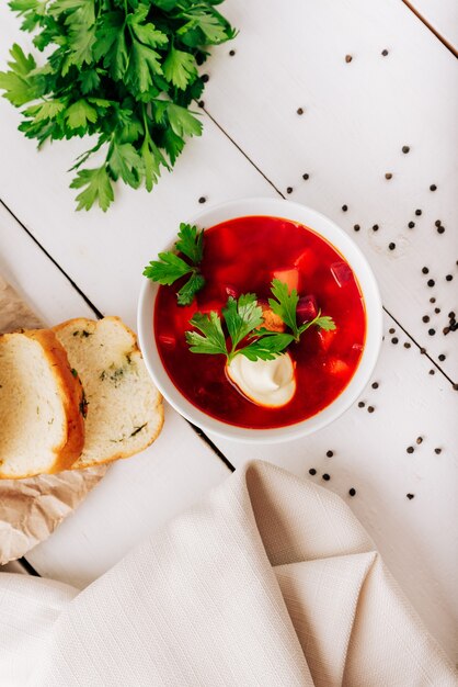 Barszcz ze świeżym pieczywem na naturalnym drewnianym tle. Barszcz czerwony ze świeżym pieczywem