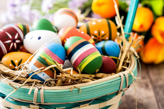 Barwioni Easter jajka w koszu na drewnianym stołu zakończeniu up