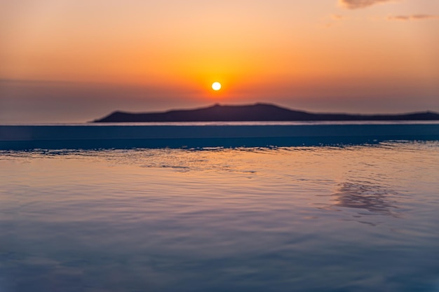 Basen bez krawędzi na dachu o zachodzie słońca na wyspie Santorini, Grecja. Piękny zachód słońca przy basenie?