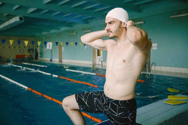 Basen. Sportowe sportowiec zakładanie czapki. Przygotowanie do treningu pływackiego.