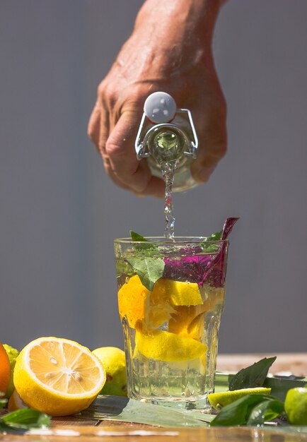 Basil Smash Gin Koktajl Alkoholowy Ze świeżymi Liśćmi Bazylii I Cytrusami. Pić W Zamrożonym Ruchu, Krople W Plusk Płynu, Strumień Soku, Plaster Limonki W Locie. Letni Zimny Napój