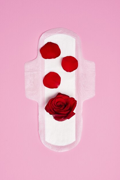 Bawełniana podpaska higieniczna na różowym tle z czerwoną różą, koncepcja miesiączki