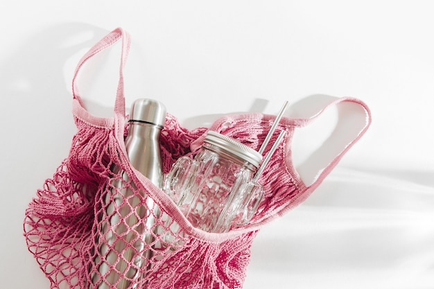 Zdjęcie bawełniana torba z siatki z metalową butelką wielokrotnego użytku, szklanym słojem i słomką. koncepcja zero odpadów