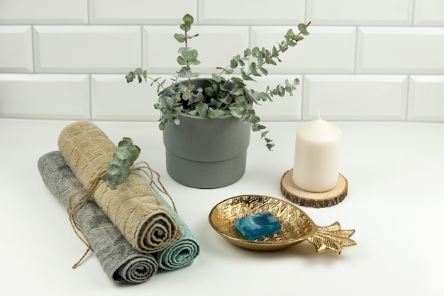 Bawełniane ręczniki w neutralnym kolorze z gałązką eukaliptusa leżą na stole w nowoczesnej łazience
