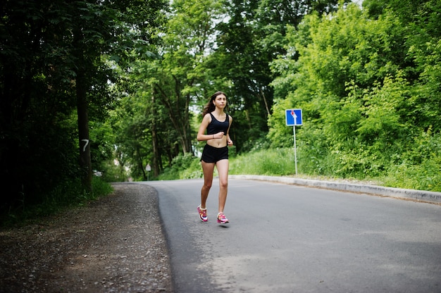 Bawi się dziewczyny przy sportswear bieg w zielonym parku i trenuje przy naturą.