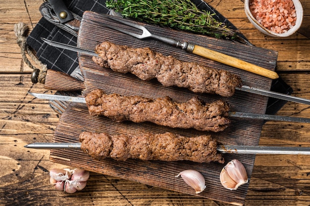 Zdjęcie bbq grillowany adana kebab na szaszłykach z mielonego mięsa jagnięcego wołowego drewniane tło widok z góry