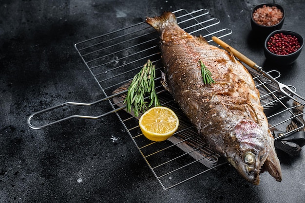 BBQ pieczona troć wędrowna grillowana ryba na grillu z rozmarynem Czarne tło Widok z góry Wolne miejsce na tekst