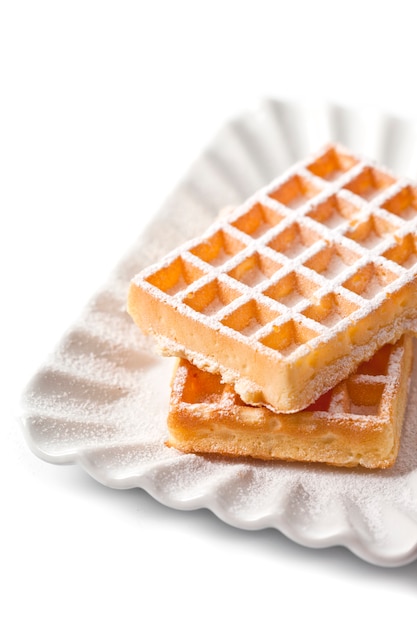 Belgia waffers z cukieru proszkiem na ceramicznym talerzu odizolowywającym na białym tle.