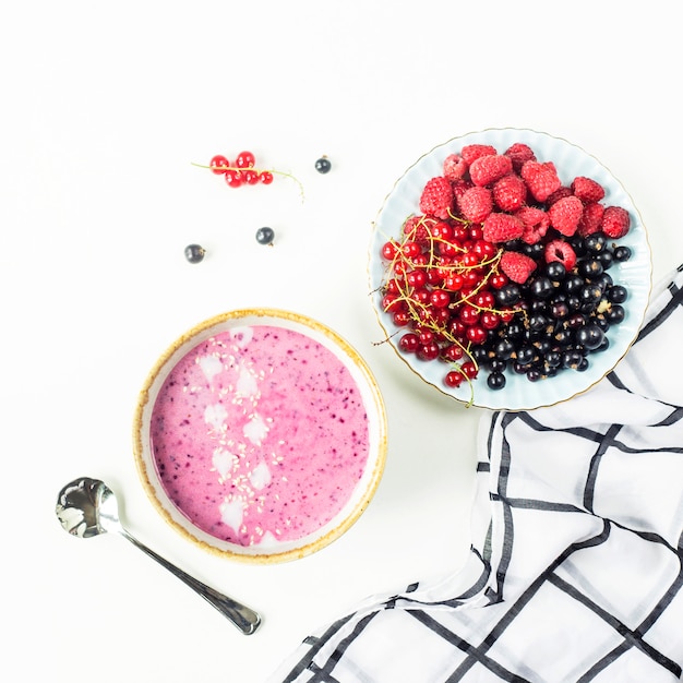 Berry smoothie w misce obok płyty z malin i czarnych i czerwonych porzeczek