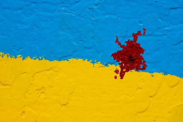 Betonowa ściana Pomalowana Na żółto I Niebiesko Jak Ukraińska Flaga Z Krwistoczerwoną Plamą Po Kuli