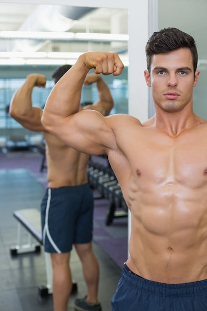 Bez koszuli mięśniowy mężczyzna napina mięśnie w gym