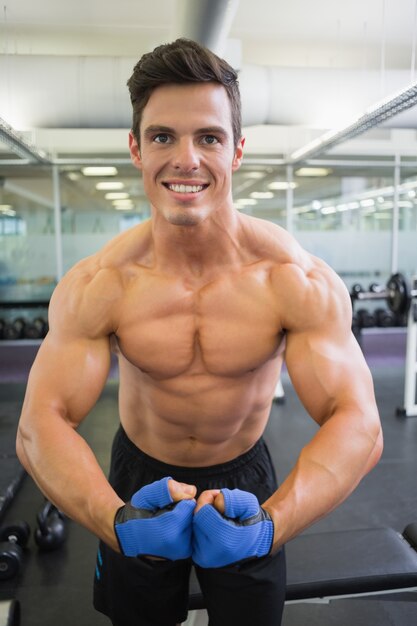 Bez koszuli mięśniowy mężczyzna napina mięśnie w gym