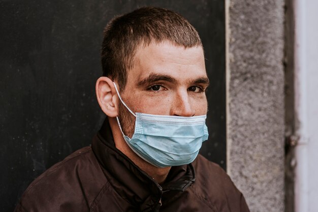 Bezdomny mężczyzna z maską medyczną na zewnątrz