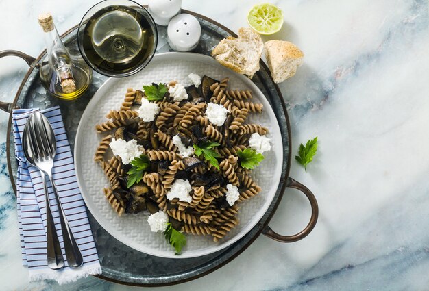 Bezglutenowy makaron z półtłustej mąki farro z grzybami portobello i serem ricotta na tacy na marmurowym stole. zdrowe przepisy wegetariańskie