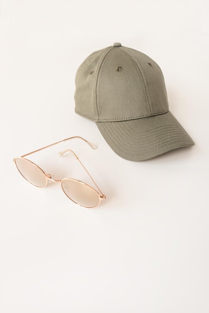 Beżowa czapka i okulary przeciwsłoneczne na białym tle Kobieca modna tkanina i koncepcja akcesoriów Neutralny zakurzony kolor