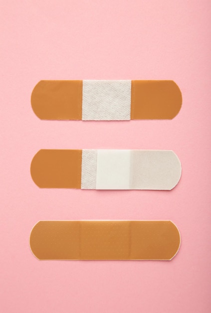 Beżowe bandaże samoprzylepne na różowym tle Plastry medyczne Zdjęcie pionowe