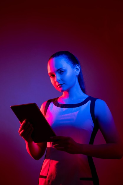 Bezpieczeństwo sieci Prywatność w cyberprzestrzeni Technologia przyszłości Cyfrowe bezpieczeństwo informacji Pewna kobieta z neonem z tabletem w różowym niebieskim fluorescencyjnym blasku na ciemnofioletowym czerwonym