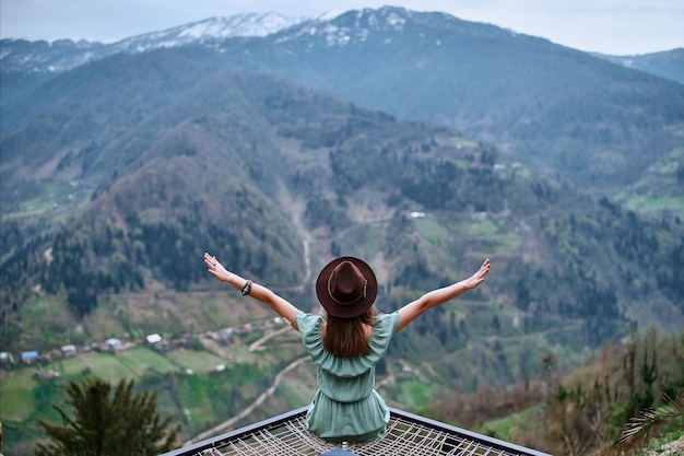 Bezpłatna podróżniczka boho chic siedząca z otwartymi ramionami i podziwiająca górski krajobraz. Spokojna i cicha koncepcja wanderlust moment, w którym osoba czuje szczęście i wolność