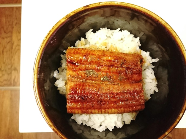 Bezpośrednio nad zdjęciem kabayaki z ryżem podawanym w misce na stole