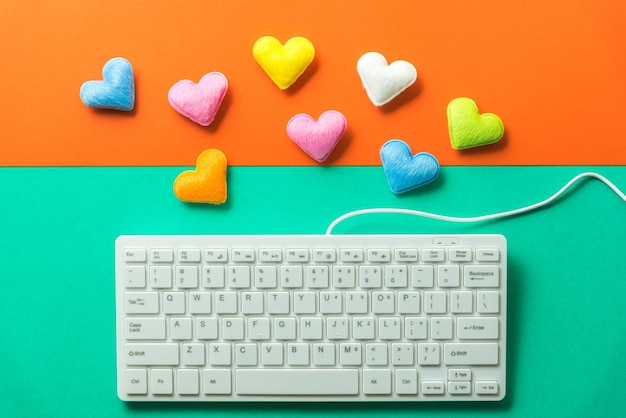 Bezpośrednio powyżej zdjęcie klawiatury komputerowej z kolorowymi kształtami serc na kolorowym tle