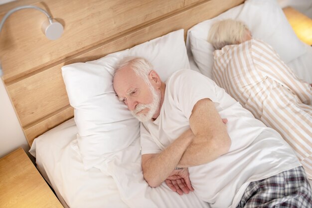 Bezsenność. Starsze małżeństwo leżące plecami do siebie w łóżku próbujące zasnąć