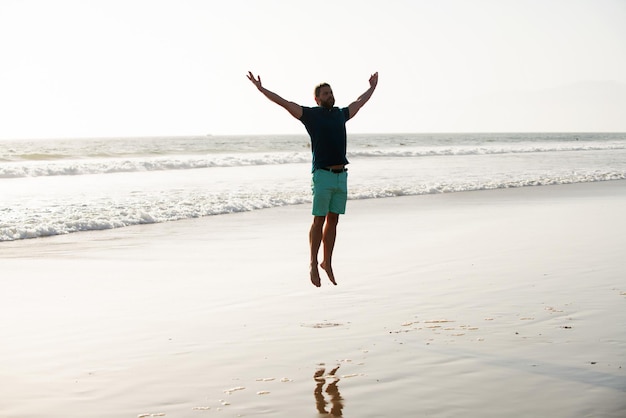 Beztroski mężczyzna skaczący po naturze Mężczyzna skacze na plaży