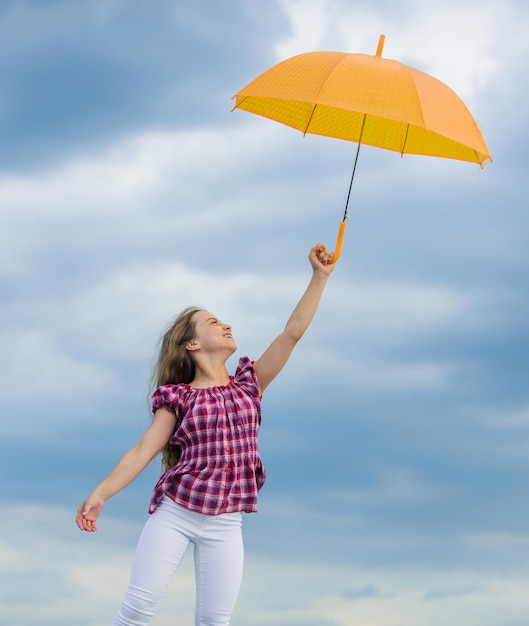 Beztroskie dziecko na zewnątrz Swoboda i świeżość Koncepcja antygrawitacyjna Radość z łatwości Prognoza pogody Gotowość na każdą pogodę Zmieniająca się pogoda Świeże powietrze Dziewczyna z parasolem Pochmurne niebo w tle