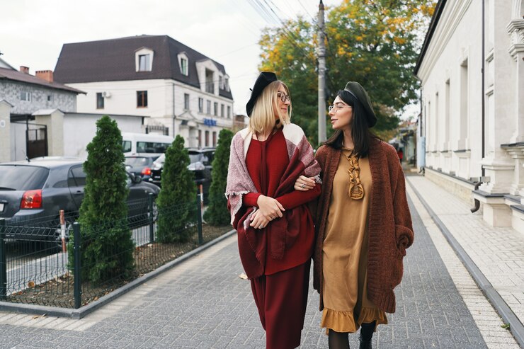 Beztroskie modele modnych kobiet w eleganckich jesiennych ubraniach i okularach. Młode dziewczyny moda w stylowe wełniane ubrania i kapelusze na miejskiej ulicy, portret jesień.