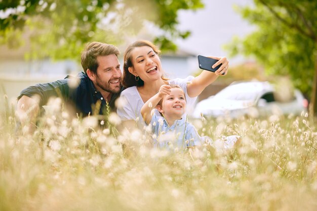 Beztroskie rodzinne dni. Ujęcie młodej rodziny robiącej selfie podczas spędzania czasu na łonie natury.