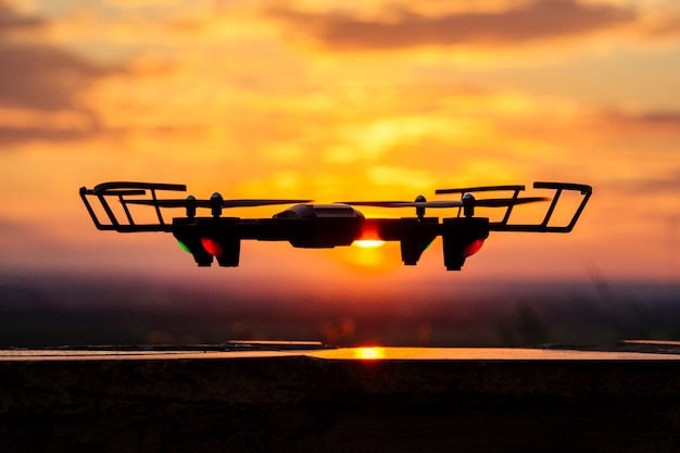 Bezzałogowy dron na tle zachodzącego słońca w locie