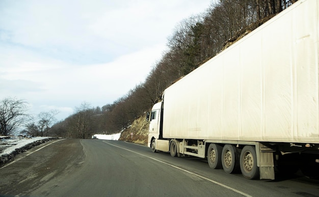 Zdjęcie biała ciężarówka z naczepą przejeżdżająca autostradą