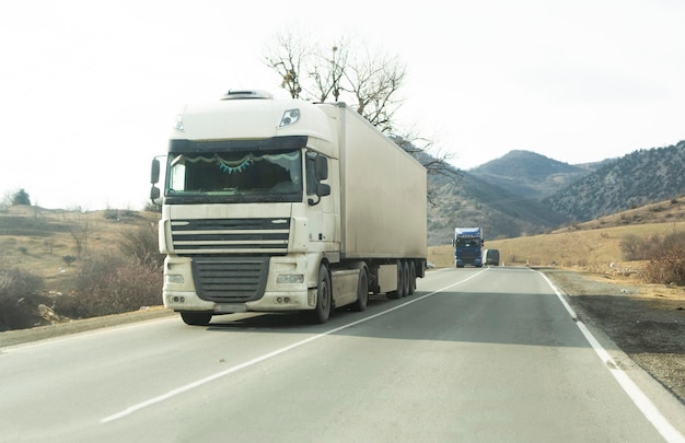 Biała ciężarówka z naczepą przejeżdżająca autostradą