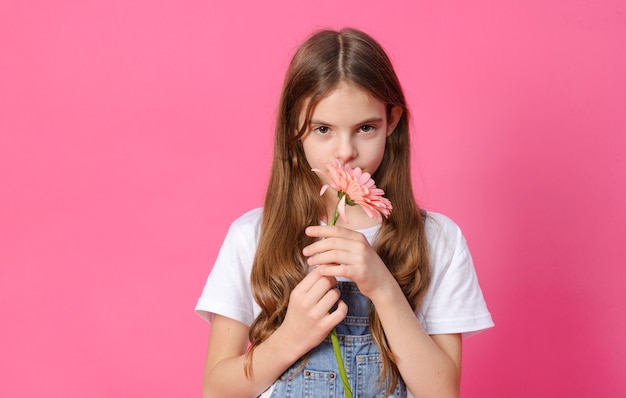 Biała Dziewczynka 10 Lat W Dżinsowej Koszuli Z Różowym Kwiatem Gerbera W Dłoniach Na Różowej, Nastolatce