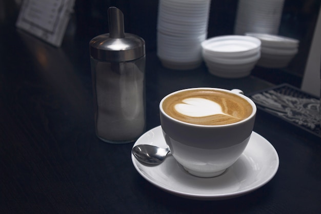Biała filiżanka do kawy z latte w kształcie serca lub cappucino w kawiarni.