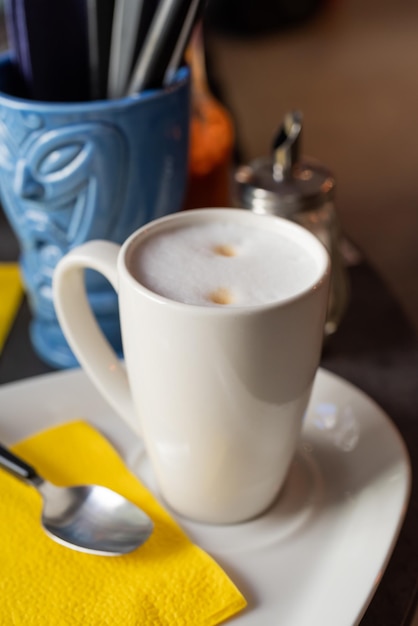 Biała filiżanka kawy cappuccino na makieta stołu w restauracji