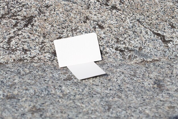 Biała karta leży na ziemi przed kamienną powierzchnią.