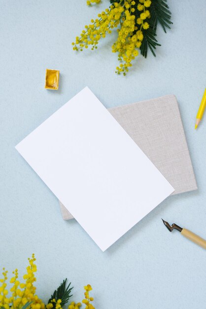 Biała kartka papieru do kopiowania tekstu otoczona wiosna mimoza notatnik żółty ołówek akwarele