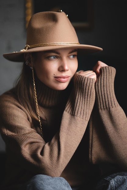 Biała kaukaska dziewczyna w brązowym swetrze i czapce z rondem