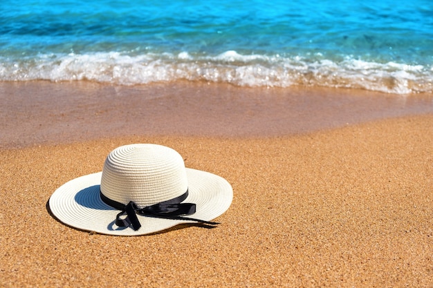 Biała kobieta słomkowy kapelusz r. Na tropikalnej piaszczystej plaży z błękitną żywą wodą oceanu