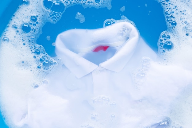 Zdjęcie biała koszulka polo moczona w proszku rozpuszczającym wodę w proszku, szmatką do prania.