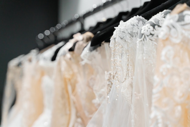 Biała kremowa suknia ślubna na wieszakach w salonie ślubnym.