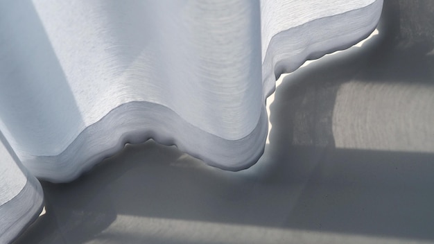 Biała kurtyna rozwiana przez wiatr i szary kolor ceramicznych płytek podłogowych zbliżenie tekstury i kąt widzenia z góry