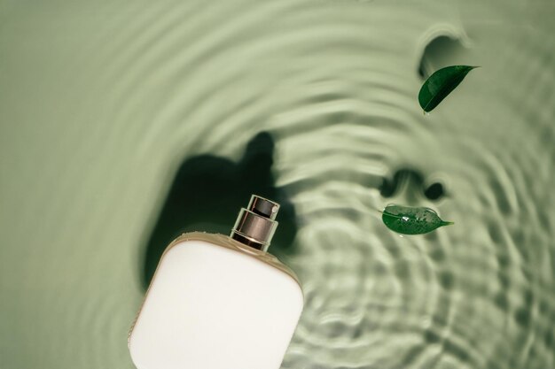 Biała kwadratowa butelka perfum na zielonym przezroczystym odbija pomarszczona fala powierzchnia wody kopia przestrzeń liście Ficus