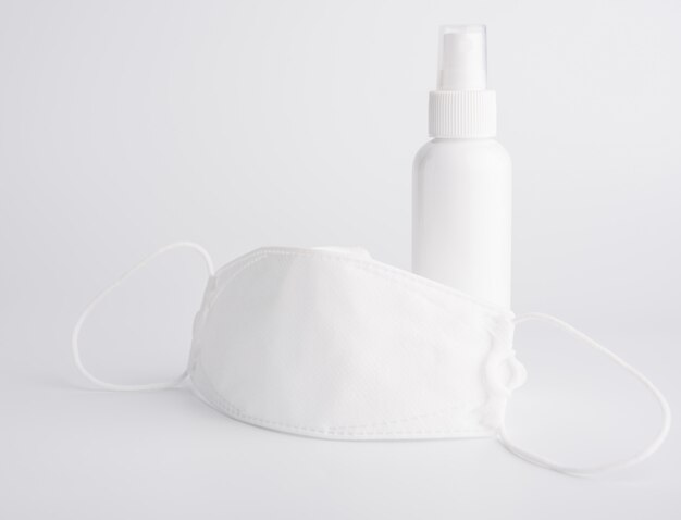 Biała maska do noszenia ochrony przed zarazkami i butelki z alkoholem lub środkiem dezynfekującym do rąk do mycia rąk w celu ochrony przed zestawem koronawirusa