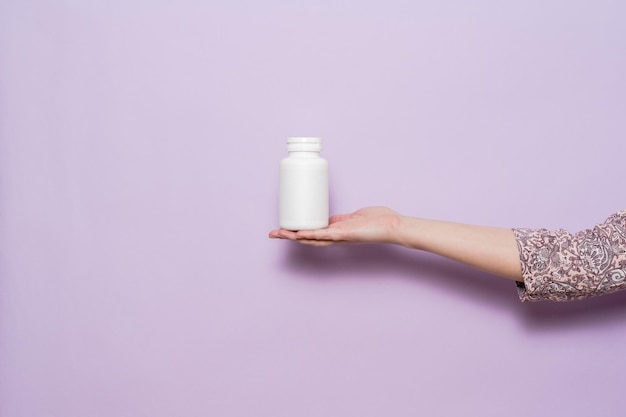 Biała plastikowa butelka w kobiecej dłoni Opakowanie na kapsułki na pigułki lub suplementy