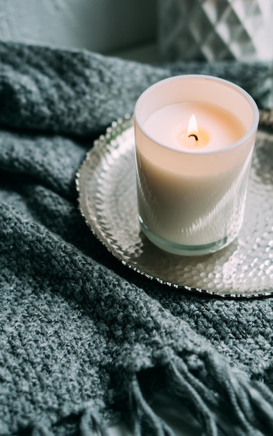 Biała płonąca świeca w szklanym świeczniku na zabytkowej metalowej tacy ciepły przytulny dom
