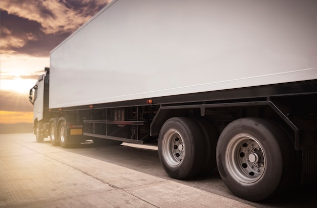 Biała półciężarówka na parkingu na wieczornym niebie słońca. Przemysł towarowy transport drogowy transportem samochodowym.