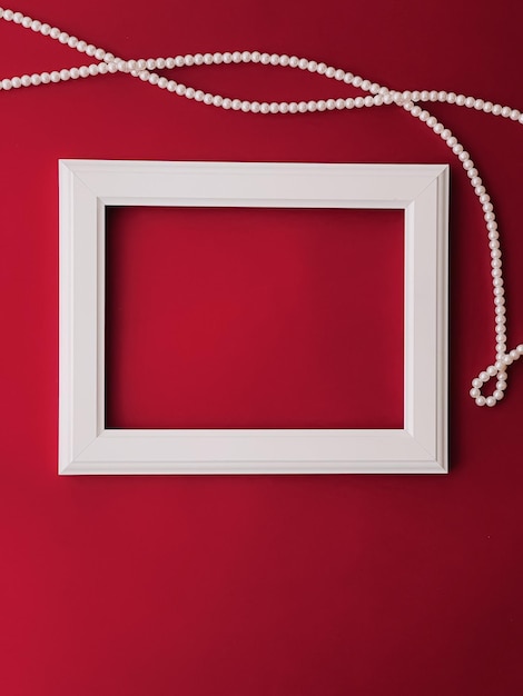 Biała pozioma ramka artystyczna i biżuteria z pereł na czerwonym tle jako grafika flatlay lub koncepcja albumu fotograficznego